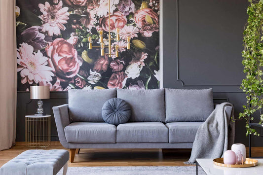 blanket-on-grey-couch-in-living-room-interior-with-flowers-wallpaper-and-lamp-on-table.jpg